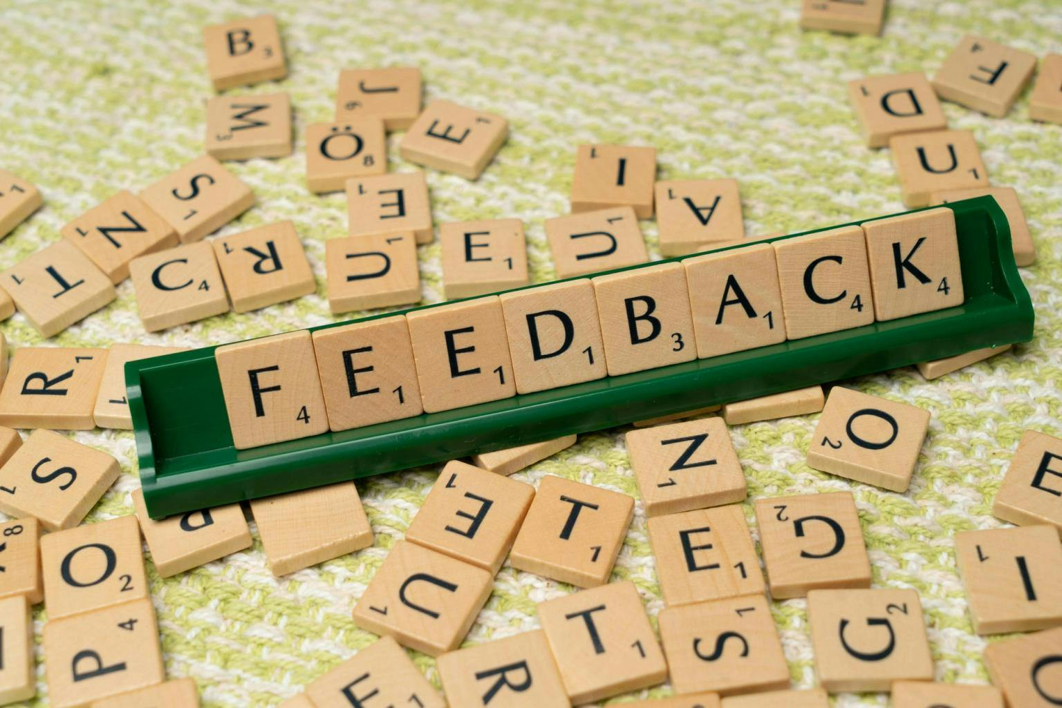 Scrabble pieces in a rack spell out the word 'FEEDBACK'