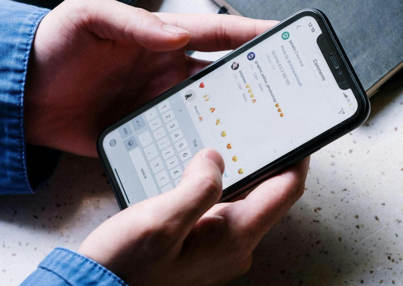 A person holds a smartphone and responds to comments on a post