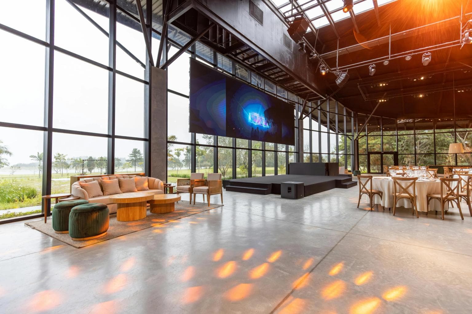 An empty conference venue with sofa, tables and a stage with screen.