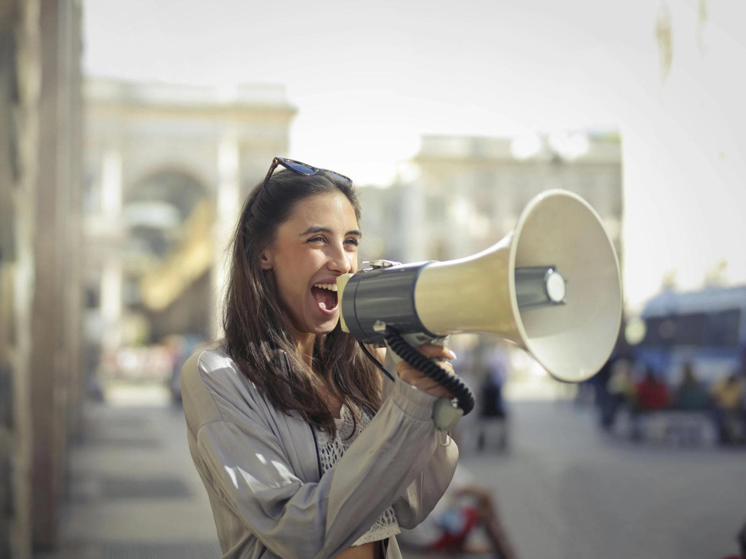 A woman shouts into a megaphone outside on the street.