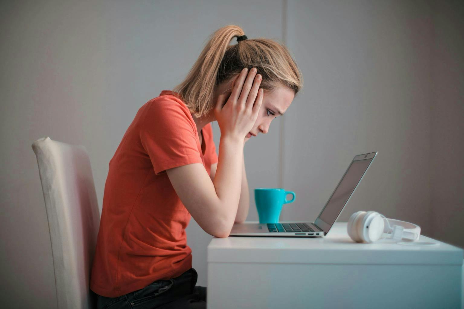 A women sits in front of a laptop with her head in her hands