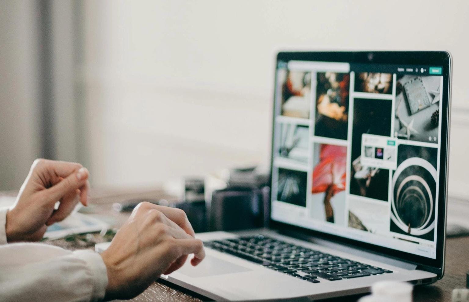 A womans hands hover over her laptop keyboard. A selection of images are on screen.