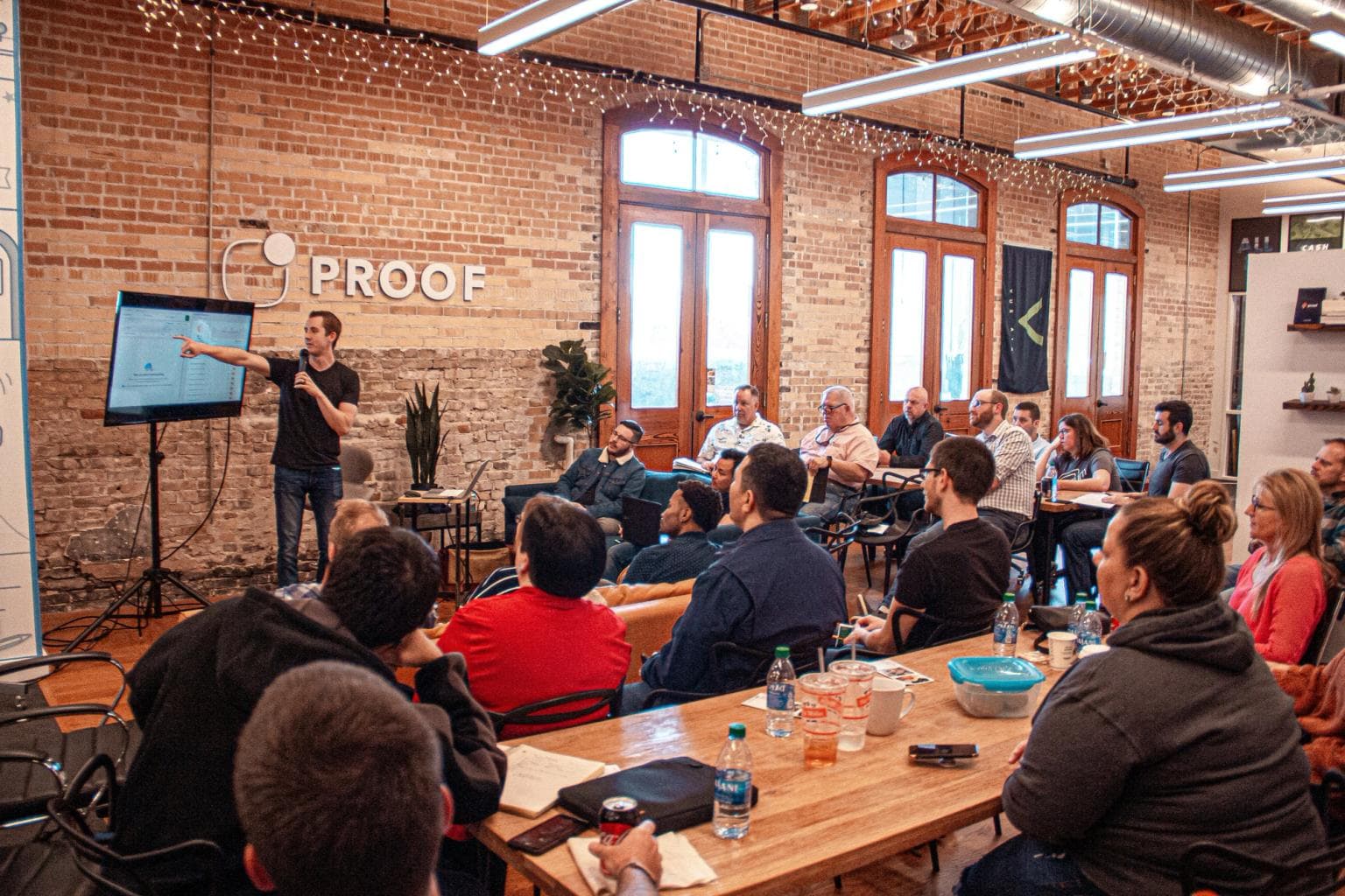 A room with people facing a speaker at the front who is showing the audience something on a screen.