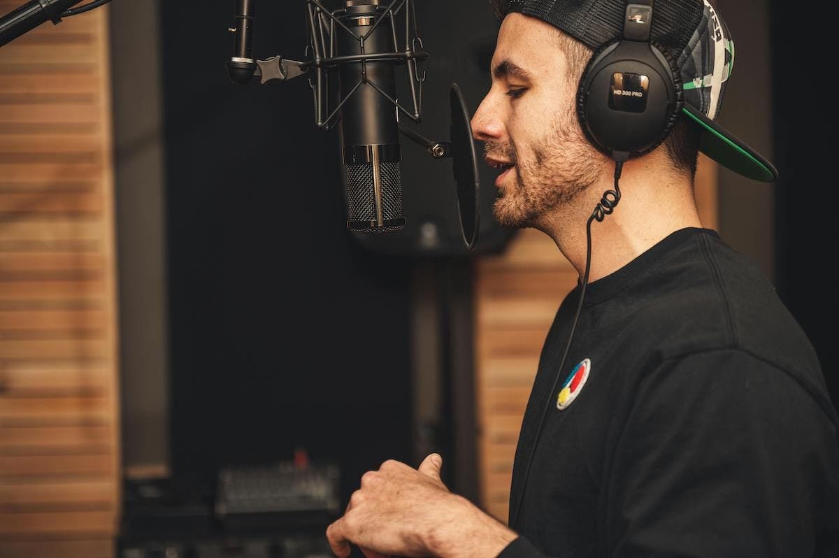 Male fitness creator talks into microphone, wearing headphones in a studio