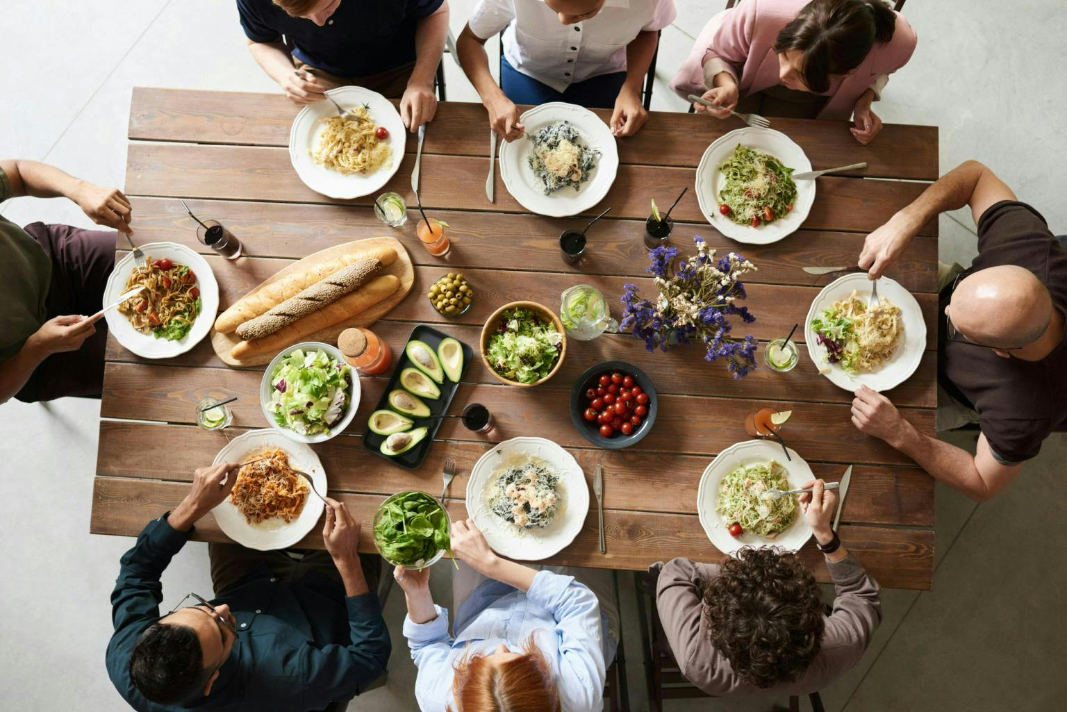 A group of people sat around a table covered with salads and bread