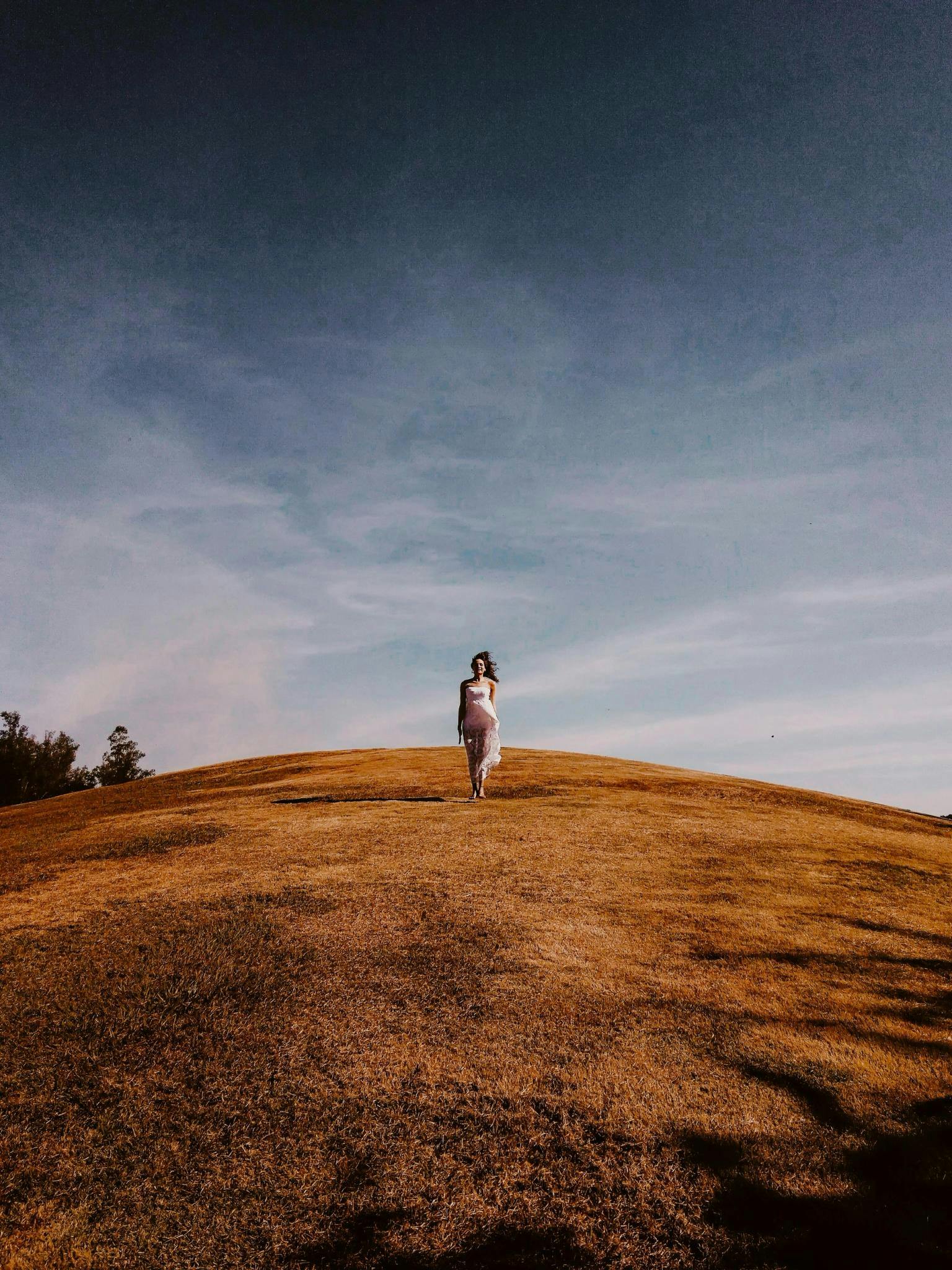 Woman walks alone on top of a hill