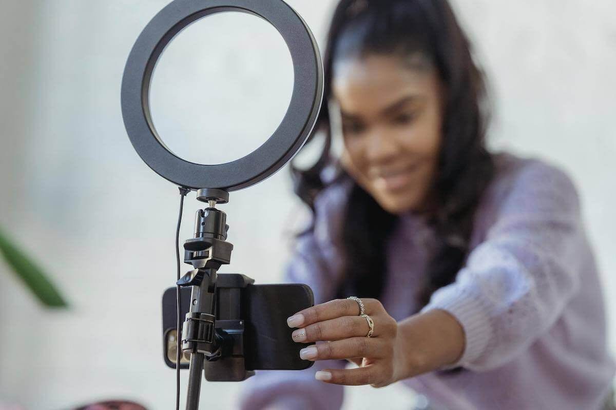 A woman lines up a phone camera and light to start filming a video for social media