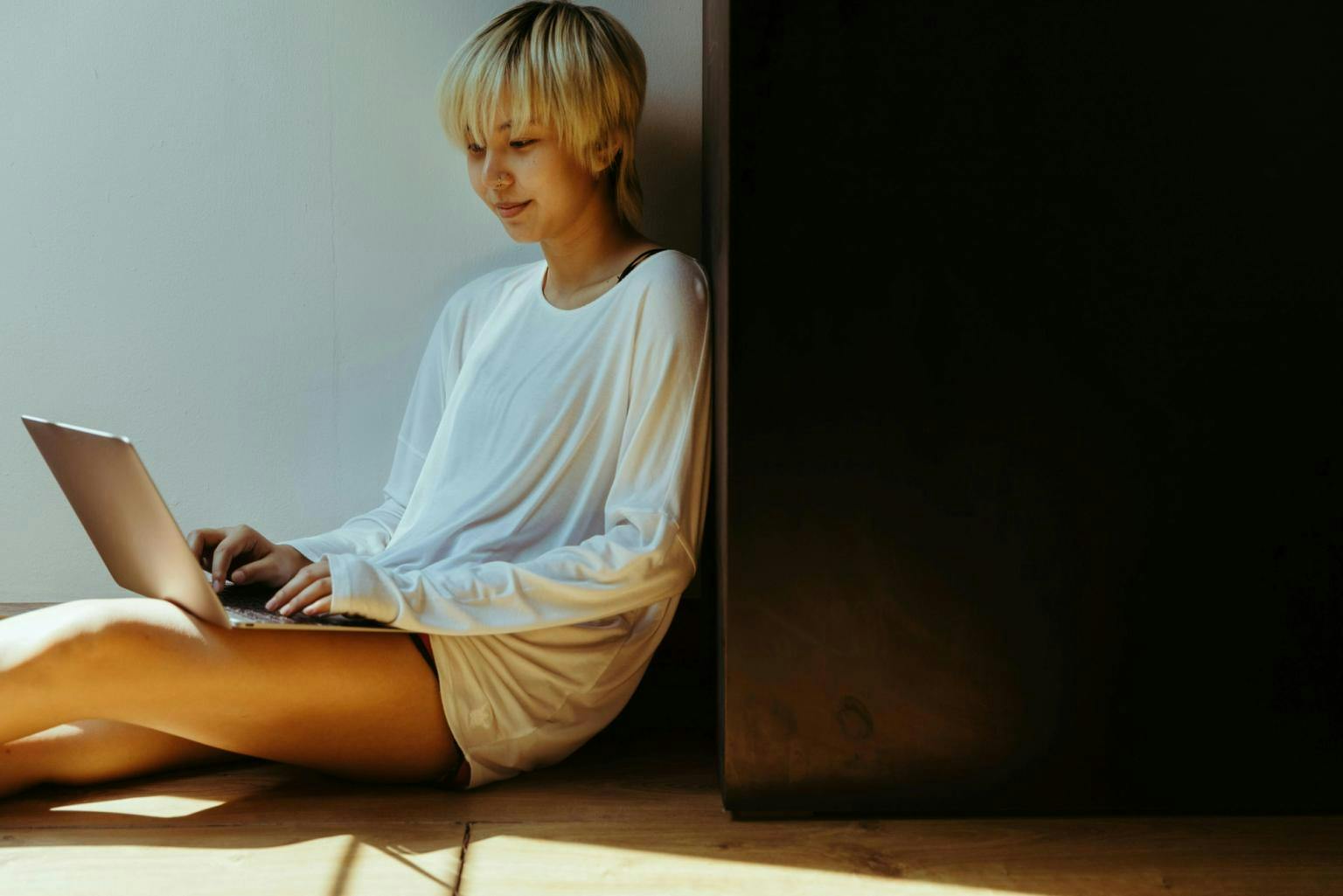 A woman sitting on the floor with her laptop, smiling