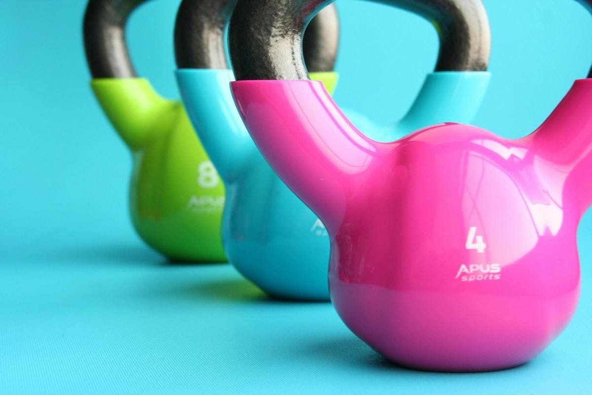 Brightly colored Kettlebells in a row against blue background