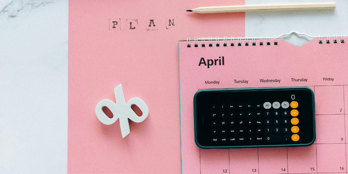 A percentage sign sits next to a calendar, with a phone calculator sitting on it. The word 'Plan' is stamped on pink card.